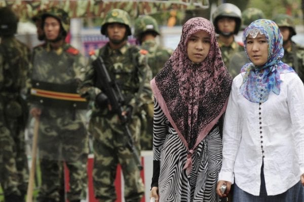 Two ethnic Uighur women pass Chinese paramilitary policemen