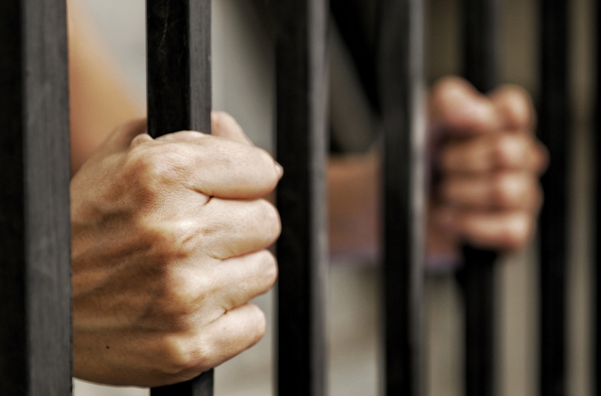 Hands prisoner holding black metal bars