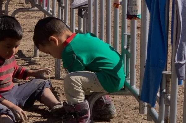 Two migrant boys are seen playing in the mud