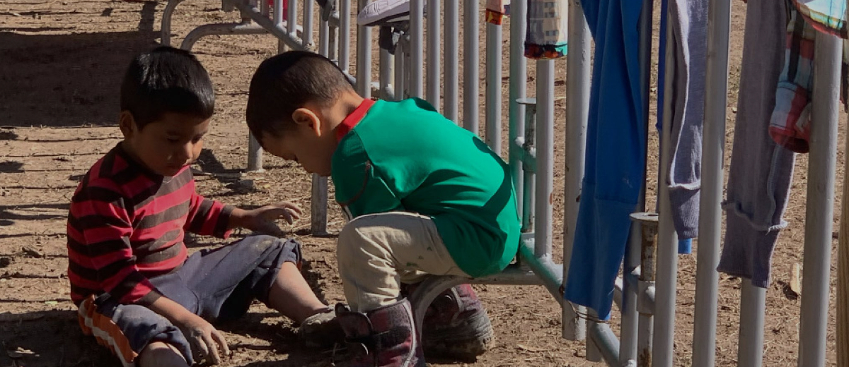 Two migrant boys are seen playing in the mud