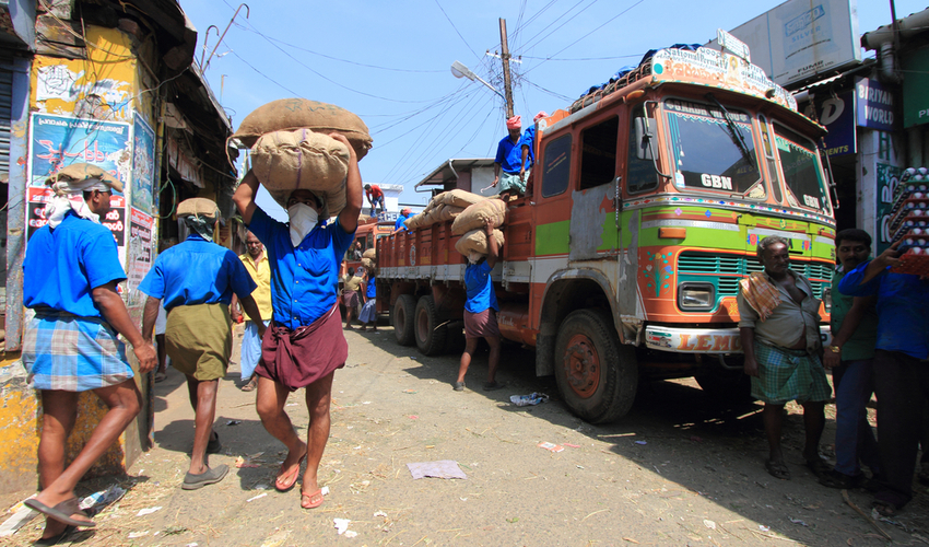 Unidentified head load workers unloading gunny bags from a truck in the market