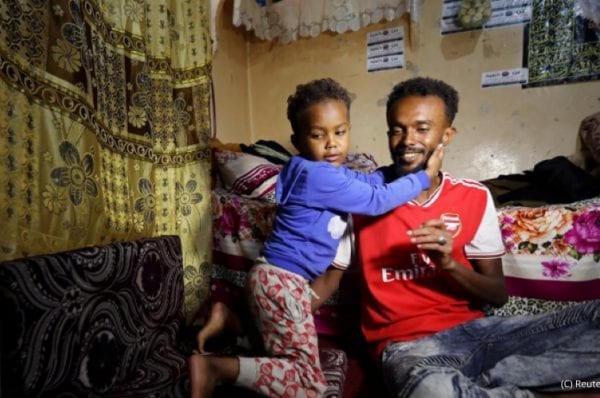 Somali refugee Bader Abdullah Hassan sits with his son, Muhammad, at their house in Sanaa, Yemen