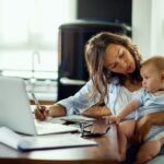 young working mother planning home budget while being with her baby at home.