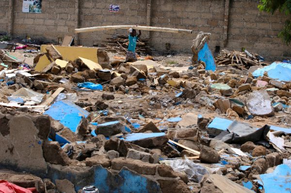 Within the wake of the demolition of their camp in Ghana, Wendell Elijah Mallobe sits in the midst of the flotsam and jetsam