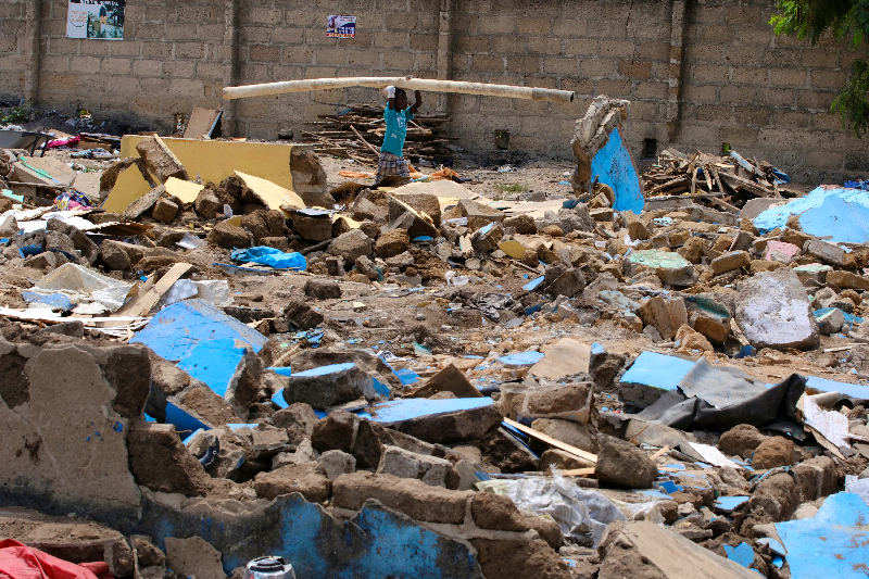 Within the wake of the demolition of their camp in Ghana, Wendell Elijah Mallobe sits in the midst of the flotsam and jetsam